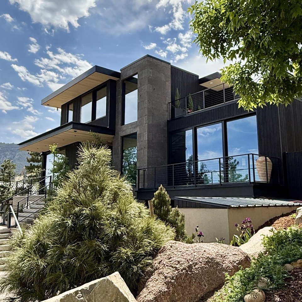 A VelareLX residence in Boulder, dark timber and stone above a planted, boulder-lined slope