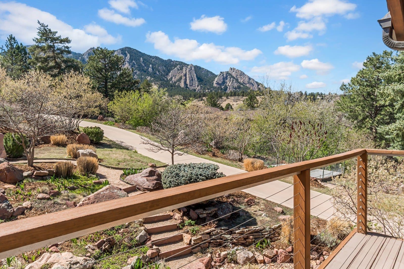A planted path and rail above open ground, looking out to the Flatirons